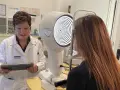 Ottico esamina paziente con un esame della vista, valutando un possibile menisco lacrimale ridotto.