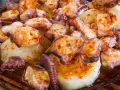 Pulpo a la gallega servido en plato de madera, con patatas cocidas y espolvoreado con pimentón.