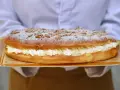 Deliciosa coca de San Juan rellena de crema, cubierta con azúcar glas y trocitos crujientes. ¡Perfecta para celebrar!