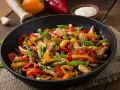 Straccetti di pollo con peperoni colorati e fagiolini, un piatto saporito e invitante servito in padella.