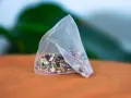 Un sachet de tisane pour anémie, rempli d'herbes et de pétales de fleurs colorés, repose sur un tissu orange.