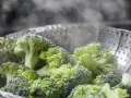 Zielony, parujący brokuł na parze w metalowym wkładzie. Zdrowy posiłek w przygotowaniu.