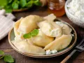 Pyszne pierogi z serem, jak u babci. Delikatne ciasto i kremowe nadzienie, posypane świeżym twarogiem i miętą.
