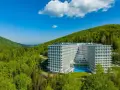Nowoczesny Crystal Mountain Hotel Wisła otoczony zielonymi wzgórzami, z basenem i tarasami.