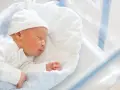 Śpiący noworodek w czepku z napisem "DADDY". To idealny moment na becikowe dla kogoś tak małego.