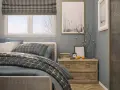 Ideas para decorar una habitación: cama con textiles grises, mesita de noche de madera con adornos y cuadros en la pared.