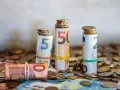Zwijane banknoty euro i monety, symbolizujące kwotę darowizny wolną od podatku, tworzą stosy na tle innych monet.