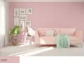 Jasnoróżowy salon z kanapą, rośliną i ramkami na ścianie.