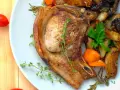 Une côte de porc savoureuse accompagnée de légumes rôtis, de pommes de terre et de tomates cerises.