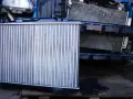 Nowa chłodnica samochodowa obok starej, zamontowanej w aucie.