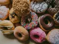 Kolorowe pączki, każdy z nich ma inną polewę i posypkę. Zastanawiasz się, ile kalorii ma pączek?