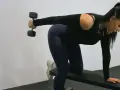 Kvinna tränar triceps med hantlar på en bänk.