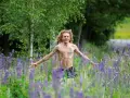 En man med lockigt hår och tatueringar står i en äng full av lila lupiner. Han ser ut att njuta av naturen, kanske som en del av ett avsnitt av "spring snyggt podden".