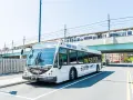 A white EZRide bus, offering fare-free transit from Boston to Cambridge, MA, drives past an elevated train station.