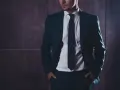 Elegancki mężczyzna w garniturze, z rękami w kieszeniach. Kim jest referent? To ktoś, kto reprezentuje, dba o szczegóły i buduje zaufanie.