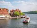 Rejsy statkiem po jeziorze to świetny sposób, by zobaczyć, co można zwiedzić w Mikołajkach. Widok na urokliwe kamieniczki i zielone lasy.