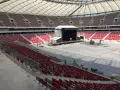 Przygotowania do koncertu Depeche Mode w Warszawie. Ogromny stadion z pustymi czerwonymi trybunami i sceną w budowie.