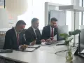 Trzech mężczyzn w garniturach przy biurku. Jeden pisze, drugi patrzy na telefon, trzeci rozmawia przez telefon. Czyżby to byli best s.a. oszuści?
