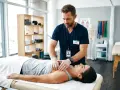 Fizjoterapeuta wykonuje masaż klatki piersiowej, pokazując jeden z rodzajów fizjoterapii.