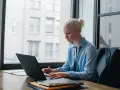Donna bionda lavora al laptop, analizzando dati per ottimizzare lo stipendio dell'e-commerce manager.