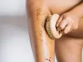 Exfoliación corporal con un cepillo de madera y un scrub para ayudar a como hidratar la piel desde dentro.