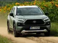 Zielona Toyota RAV4 jedzie po piaszczystej drodze, otoczona słonecznikami. To jeden z najmniej awaryjnych aut, gotowy na każdą przygodę.