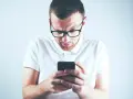 Zastanawiasz się, skąd firma windykacyjna ma Twój numer telefonu? Mężczyzna w okularach patrzy zdezorientowany na ekran smartfona.