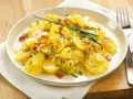 Ein Teller mit Kartoffelsalat mit Speck, garniert mit Schnittlauch. Ein Klassiker, der immer schmeckt.