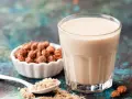 Un verre de lait de souchet crémeux, à côté d'une coupelle de tubercules et d'une cuillère de poudre.