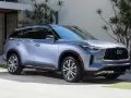 Elegancki, srebrny Infiniti SUV zaparkowany przed nowoczesnym domem z bujną roślinnością.