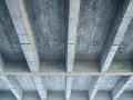 Betonowy strop z widocznymi belkami i płytami. Szukając, jaki strop najtańszy, warto rozważyć takie proste konstrukcje.
