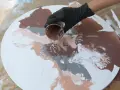 Main brune versée sur un tableau pouring acrylique blanc, créant des motifs abstraits.