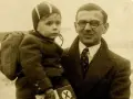 Nick Winton porte un enfant sur son bras, un petit garçon avec un sac à dos, prêt pour un nouveau départ.