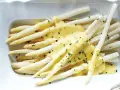 Asperges blanches nappées d'une sauce onctueuse, parsemées de ciboulette fraîche. Un délice printanier.