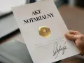 Dłoń trzyma dokument "Akt Notarialny" z pieczęcią i podpisem.