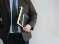 Mężczyzna w garniturze trzyma teczki. Zastanawiasz się, ile zarabia notariusz?