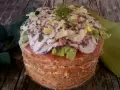 Panettone Gastronomico with sliced octopus, lettuce, and herbs on a wooden table.