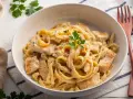Pyszny kurczak w sosie alfredo z tagliatelle, udekorowany natką pietruszki. Idealny obiad dla całej rodziny.