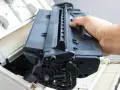 Ręka wyjmuje czarny toner z drukarki. Skorzystaj z naszej oferty bezpłatny odbiór tonerów.