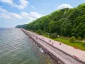 Spacer po molo południowym wzdłuż zielonego wybrzeża. Ludzie spacerują, odpoczywają na ławkach, ciesząc się pięknym dniem nad morzem.