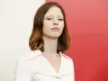 La giovane attrice protagonista del film di mia goth, con capelli castani mossi e un'espressione intensa, indossa un abito bianco.