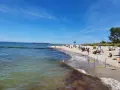 En solig tysk strand med folk som njuter av havet och sanden. En brygga sträcker sig ut i vattnet.