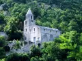 Antica chiesa in pietra su un fianco di montagna, circondata da alberi lussureggianti. I tramonti montagna qui sono magici.