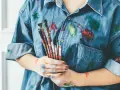 Manos manchadas de tempera y una camisa vaquera salpicada de pintura. ¡Un desafío para quitar tempera de la ropa!