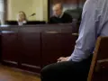 W sali sądowej mężczyzna czeka na werdykt. Czy kara grzywny jest wyrokiem? Sędziowie i ławnicy w tle.