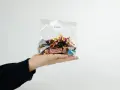 En hand håller en presentkorg i cellofan fylld med choklad.
