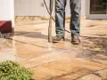 Nettoyer carrelage extérieur noirci avec un nettoyeur haute pression. L'eau projetée révèle la beauté naturelle des dalles.