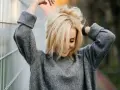 Blondynka w szarym swetrze, z włosami opadającymi na twarz. Marzy o gładkiej skórze, rozważa depilację laserową jasnych włosów.