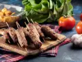 Aksamitne ćevapi na drewnianej desce, obok pomidory, czosnek i pieczone ziemniaki. Pyszny posiłek gotowy do podania.