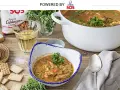 Delicioso arroz con bogavante servido en un cuenco, con una cazuela llena y una bolsa de arroz SOS al fondo.